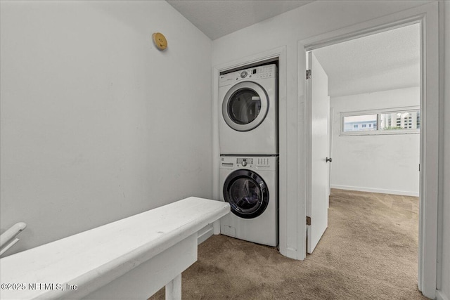 washroom featuring a textured ceiling, stacked washing maching and dryer, and light colored carpet