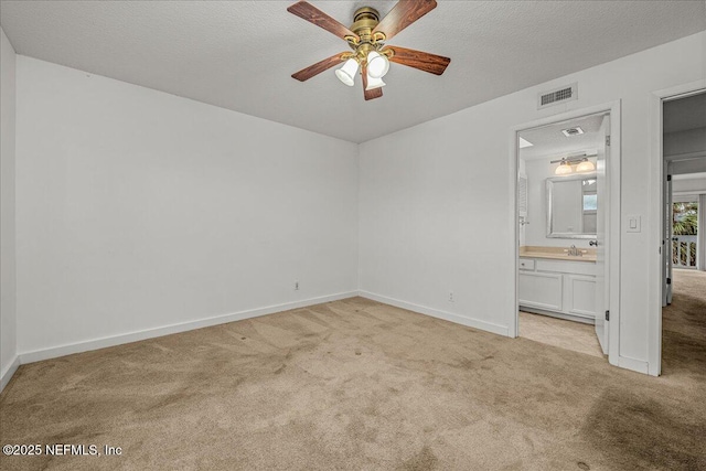 unfurnished bedroom with a textured ceiling, ceiling fan, light colored carpet, and ensuite bathroom