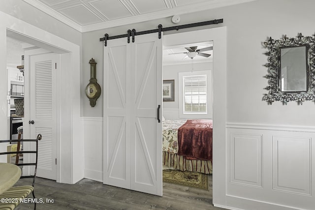 bedroom with a barn door and dark hardwood / wood-style floors