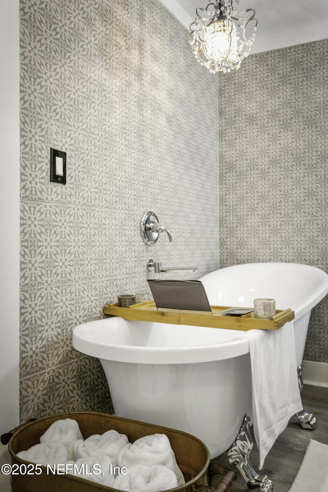 bathroom featuring a bath, a chandelier, and hardwood / wood-style floors