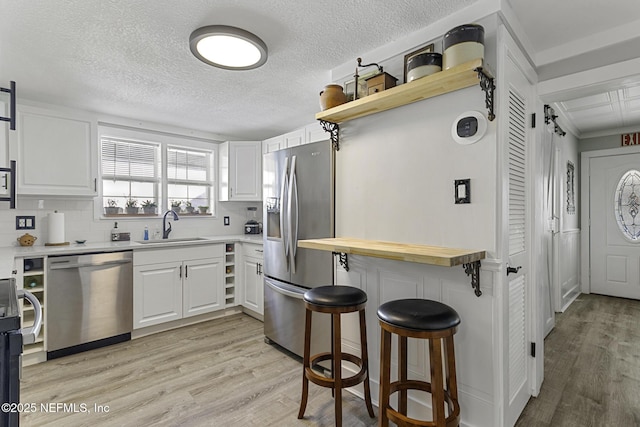 kitchen with stainless steel appliances, decorative backsplash, white cabinets, and sink