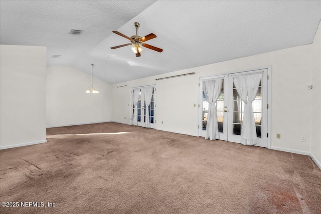 spare room featuring carpet, lofted ceiling, french doors, ceiling fan with notable chandelier, and a textured ceiling