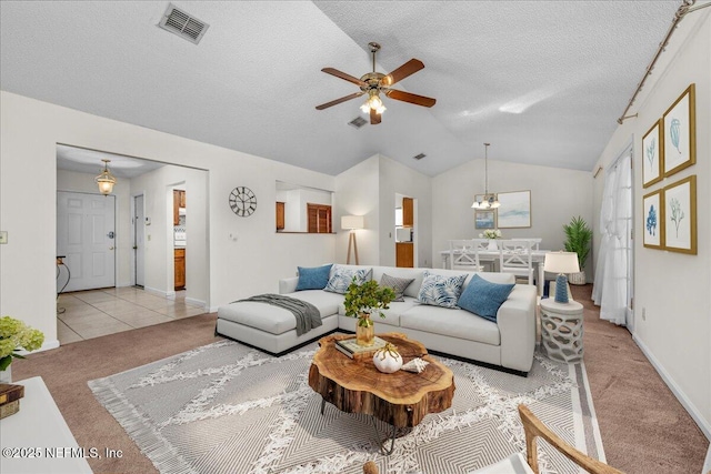 carpeted living room with a textured ceiling, ceiling fan with notable chandelier, and vaulted ceiling