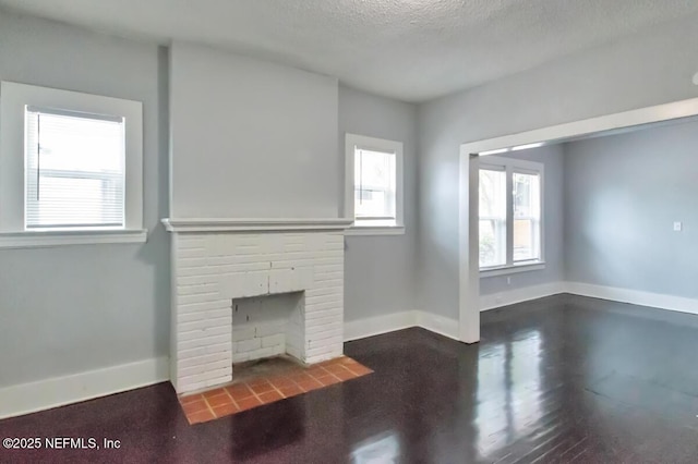 unfurnished living room with a wealth of natural light, a fireplace, and a textured ceiling