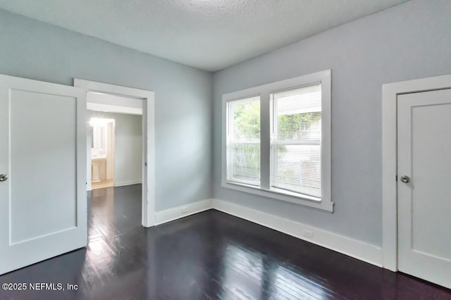 spare room with dark hardwood / wood-style flooring and a textured ceiling