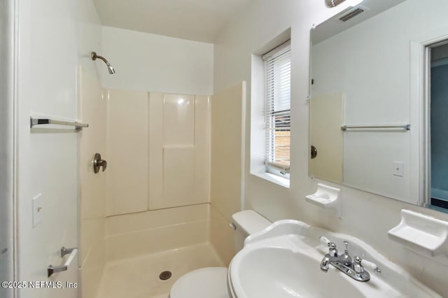 bathroom featuring a shower, toilet, and sink