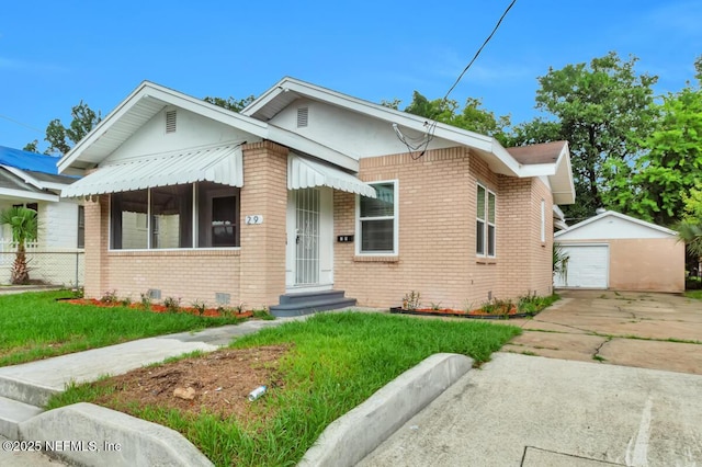 bungalow-style home featuring a garage, an outdoor structure, and a front yard