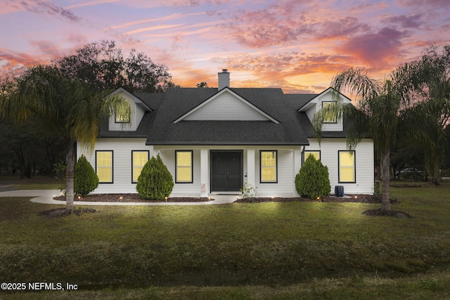 cape cod house with a yard and central AC unit