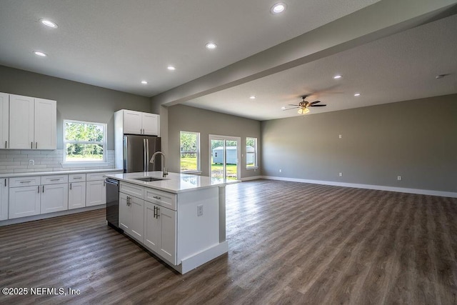 kitchen with backsplash, a center island with sink, sink, appliances with stainless steel finishes, and white cabinetry