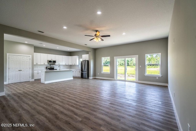 unfurnished living room with a textured ceiling, ceiling fan, dark hardwood / wood-style floors, and sink