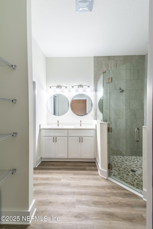 bathroom featuring wood-type flooring, vanity, and a shower with door