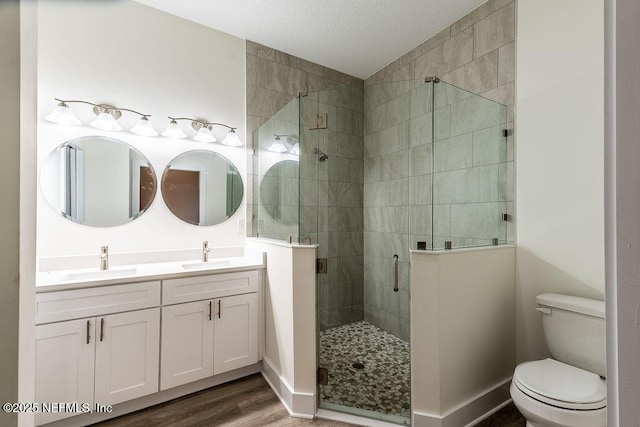 bathroom with hardwood / wood-style floors, vanity, toilet, and walk in shower