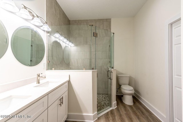 bathroom with wood-type flooring, vanity, a shower with shower door, and toilet