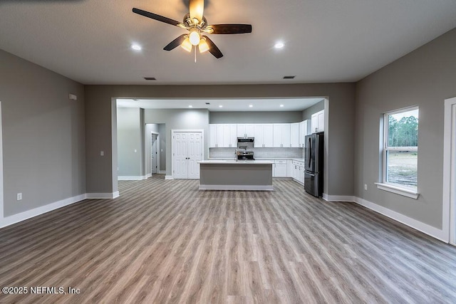 kitchen featuring white cabinets, ceiling fan, appliances with stainless steel finishes, tasteful backsplash, and a kitchen island