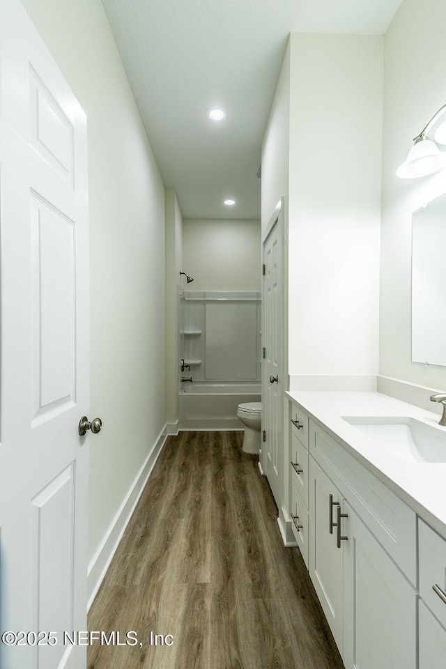 full bathroom featuring hardwood / wood-style flooring, vanity,  shower combination, and toilet