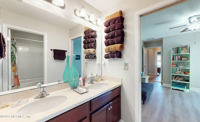 bathroom with shower / tub combo with curtain, wood-type flooring, a textured ceiling, vanity, and ceiling fan