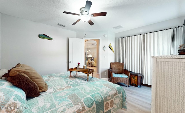 bedroom with ceiling fan, a textured ceiling, and light wood-type flooring