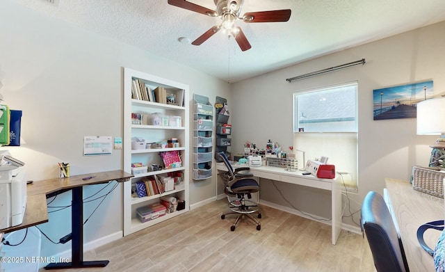 office featuring ceiling fan, light wood-type flooring, and a textured ceiling