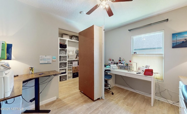 home office with ceiling fan, a textured ceiling, and light wood-type flooring