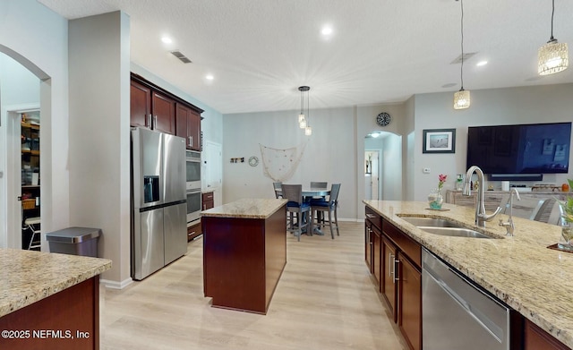 kitchen with decorative light fixtures, a center island, sink, and appliances with stainless steel finishes