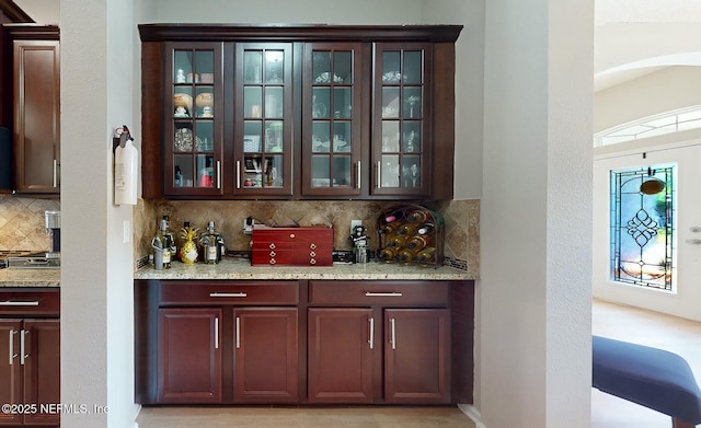 bar with light stone countertops and tasteful backsplash