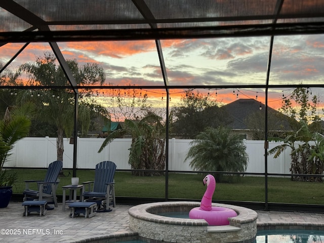 patio terrace at dusk featuring a pool with hot tub and glass enclosure