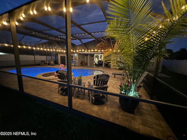 pool at night with a lanai and a patio area