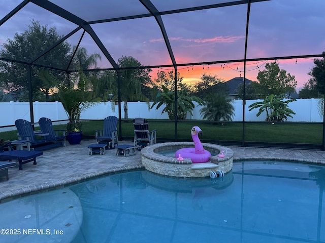 pool at dusk featuring an in ground hot tub, a lanai, and a patio area