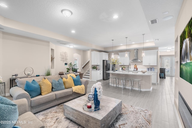 living room featuring a textured ceiling, a raised ceiling, and sink