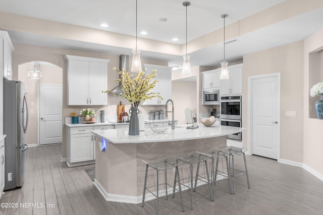 kitchen featuring a kitchen breakfast bar, white cabinetry, an island with sink, and appliances with stainless steel finishes