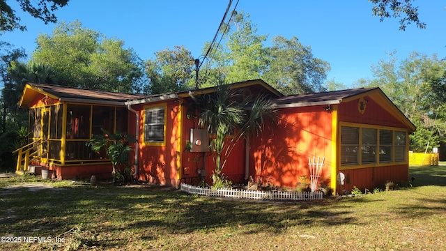 view of side of property featuring a lawn and a sunroom