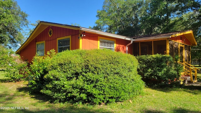 view of side of property featuring a yard and a sunroom