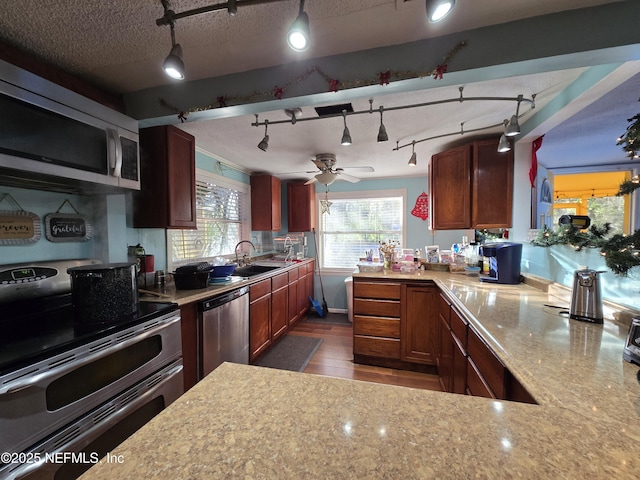 kitchen featuring appliances with stainless steel finishes, a textured ceiling, ceiling fan, decorative light fixtures, and dark hardwood / wood-style floors