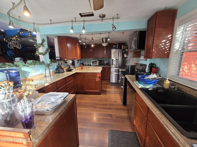 kitchen with appliances with stainless steel finishes, sink, pendant lighting, and wood-type flooring