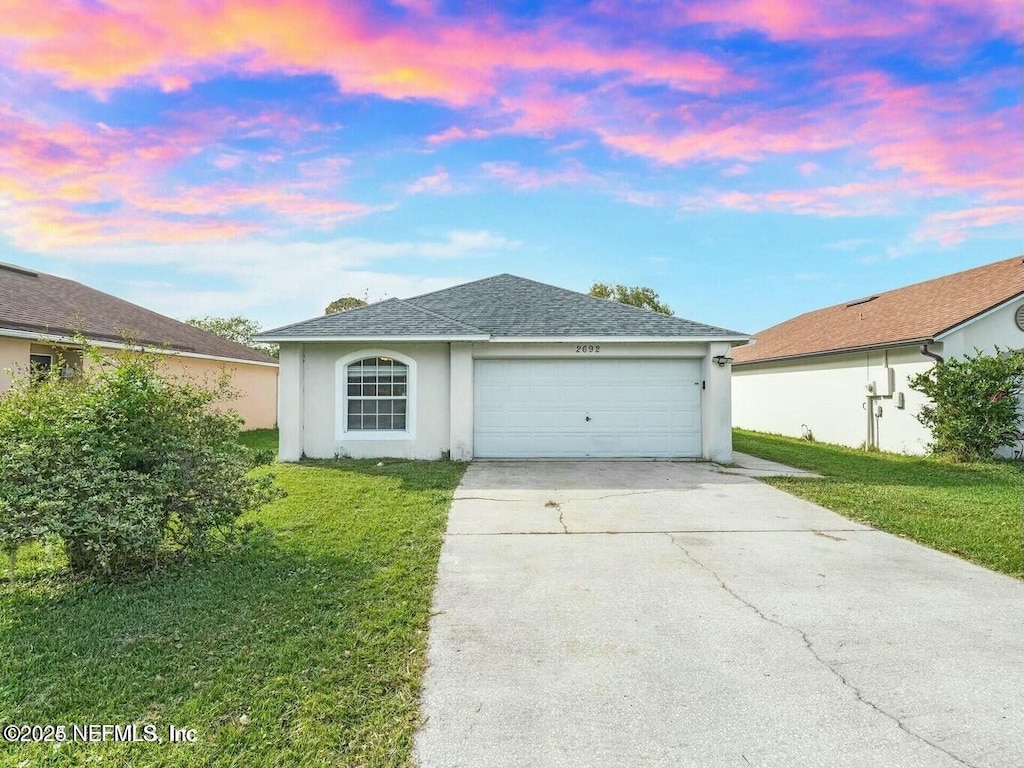 single story home featuring a garage and a yard