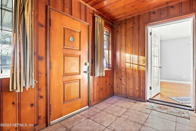 entryway with wooden walls and light tile patterned floors