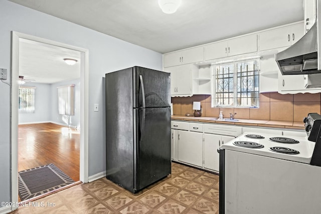 kitchen featuring white range with electric cooktop, black refrigerator, white cabinets, extractor fan, and tasteful backsplash