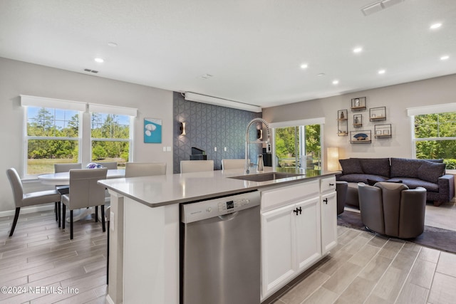 kitchen featuring white cabinets, dishwasher, an island with sink, and sink