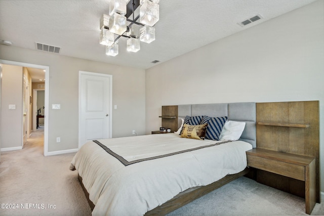 carpeted bedroom with a textured ceiling and an inviting chandelier