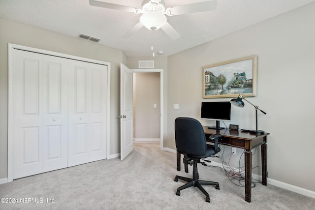 office space with a textured ceiling, ceiling fan, and light carpet