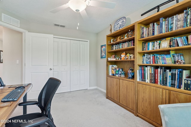 carpeted office with a textured ceiling and ceiling fan