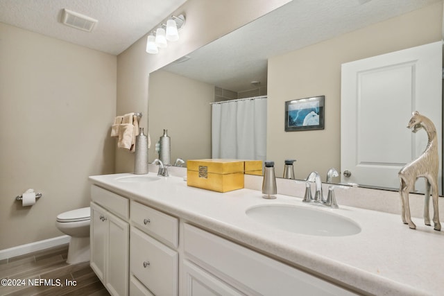 bathroom featuring a shower with shower curtain, vanity, toilet, and a textured ceiling