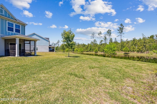 view of yard with a sunroom and a water view