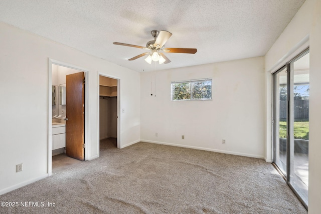 unfurnished bedroom with connected bathroom, a walk in closet, ceiling fan, and multiple windows