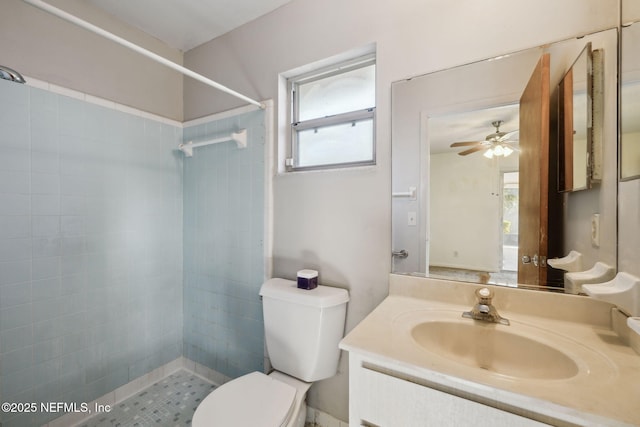 bathroom with a tile shower, vanity, toilet, and ceiling fan