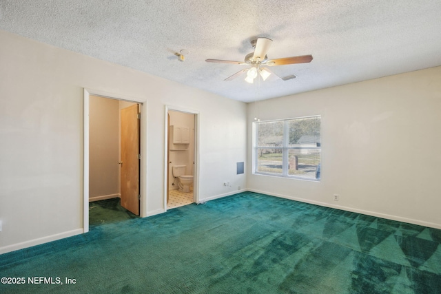 unfurnished bedroom with ceiling fan, dark colored carpet, ensuite bathroom, a walk in closet, and a closet