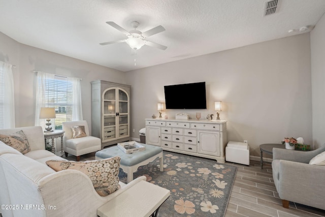 living room with a textured ceiling and ceiling fan