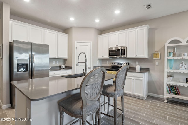 kitchen featuring a kitchen island with sink, white cabinetry, sink, and appliances with stainless steel finishes