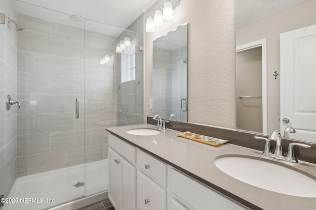 bathroom featuring a textured ceiling, vanity, and a shower with door