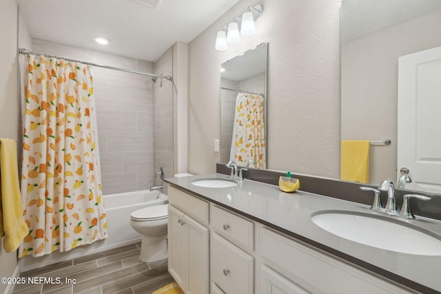 full bathroom featuring vanity, toilet, a textured ceiling, and shower / tub combo with curtain